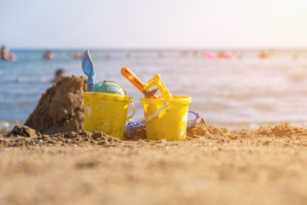 阳光明媚的日子里，孩子们在沙滩上玩水桶、铲子和铲子图片下载