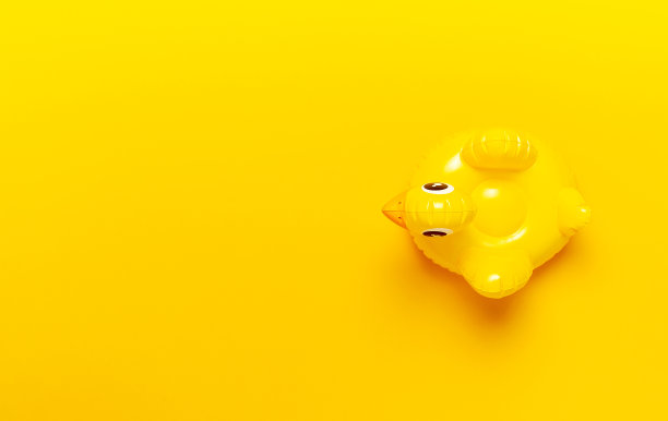 创意的夏季海滩概念。充气迷你小黄鸡或小鸭在黄色的背景下，泳池漂浮派对。平面拷贝空间。潮流充气儿童游泳玩具。布局设计图片下载