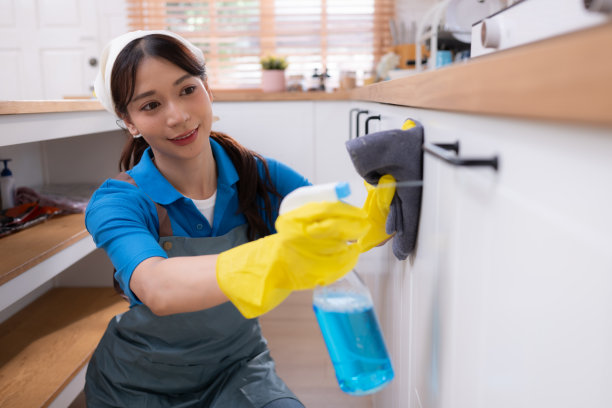 一名亚洲年轻女子正在厨房里清理台面和碗柜。做家务的概念图片下载