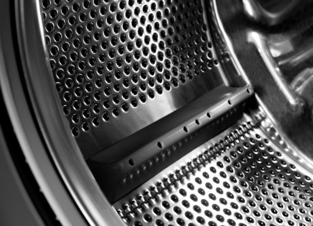 洗衣机滚筒内部。用于自动洗衣机的穿孔不锈钢滚筒。黑色和白色，金属背景图片下载