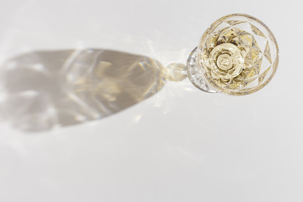 白葡萄酒装在晶莹透明的时尚玻璃中，在阳光下带有阴影和眩光，浅白灰色背景，创意夏日休息酒饮的极简概念，复制空间，俯视图图片下载