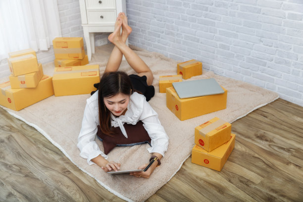 亚洲女性躺在家里的地毯上用笔记本电脑工作。图片下载