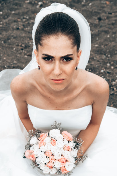 幸福的新娘穿着白色礼服坐在沙滩上图片下载