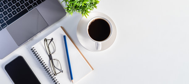 笔记本电脑和咖啡杯放在办公室的白色桌子上。使用科技，智能手机，笔记本电脑，互联网的工作理念。复制右边的空间用于设计或文本，近距离，顶视图白色背景图片下载