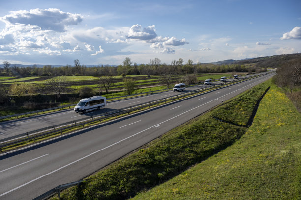 白色现代快递小件货物快递车在高速公路上快速行驶到城市郊区。白色现代舒适的旅游巴士行驶在高速公路上。旅游和旅游车旅游的概念图片下载
