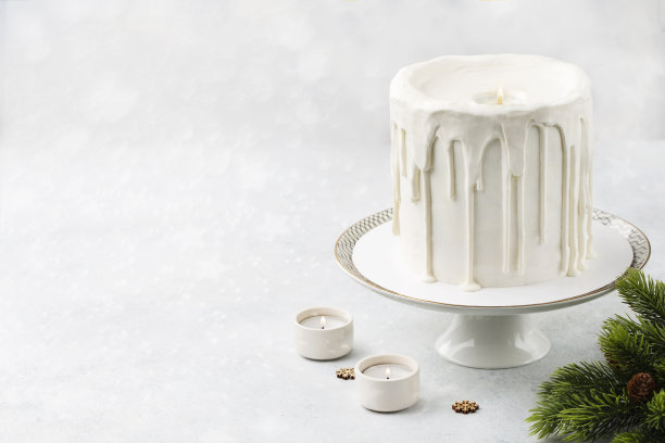 蜡烛形状的蛋糕。圣诞白色蛋糕在白色背景上与圣诞装饰，灯或冬季节日糕点食品概念。图片下载