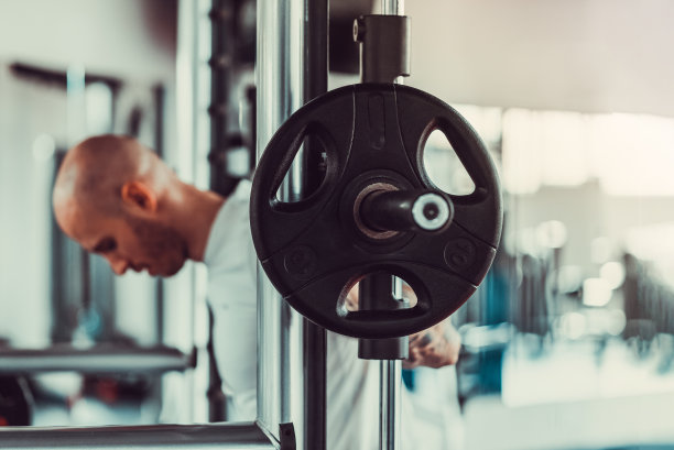 帅哥在健身房的健身机上举重，股票照片图片下载