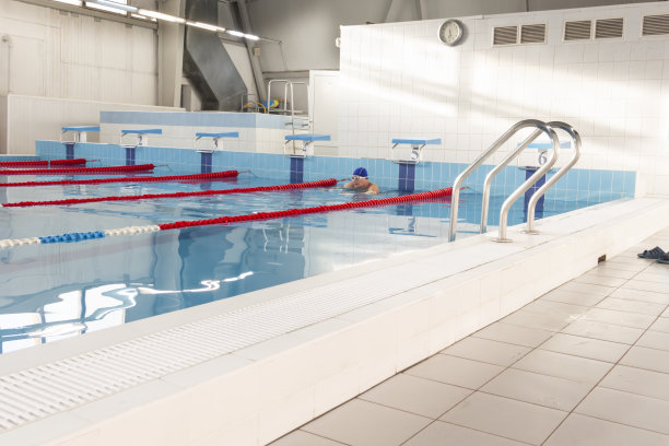 一名男运动员在蓝水中的游泳池运动中心游泳。图片下载