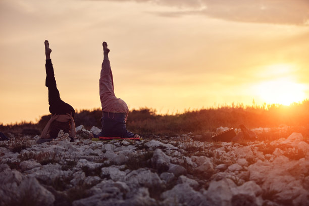 母亲和女儿一起练习瑜伽在日落日出的时间在大自然。图片下载