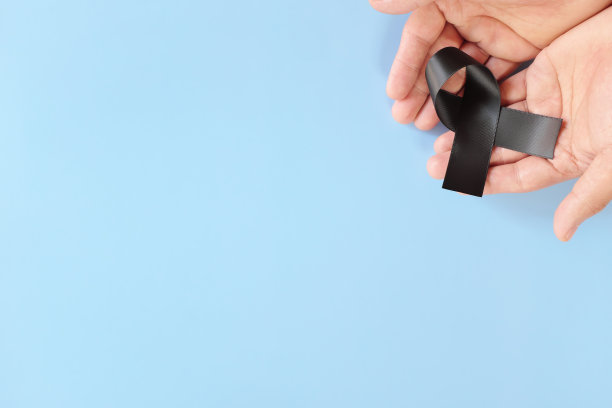 男性手持黑色丝带在蓝色背景与拷贝空间的俯视图。黑素瘤或皮肤癌，帮派预防和嗜睡意识的概念。图片下载