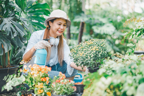 年轻女性的爱好是照顾植物，浇水，铲花。在工作休息的时候在花园里图片下载