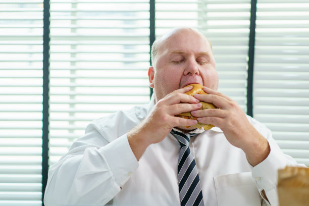 一个人在办公室吃垃圾食品。图片下载