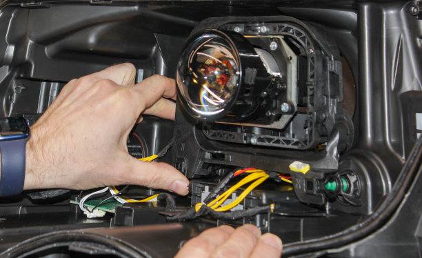 修理中的汽车前灯特写。汽车修理工把镜片安装在前灯罩里。汽车服务的概念。前照灯安装LED镜头。领导的镜头。光学恢复。图片下载