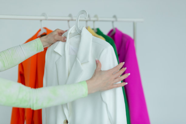 一个女人的手在白色背景的衣架上挑选衣服图片下载