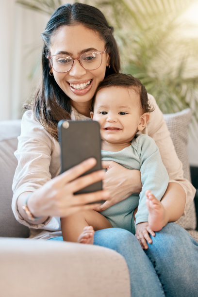 这张照片拍摄的是一名妇女坐在腿上看着自己的手机，她的孩子就在她的腿上图片下载