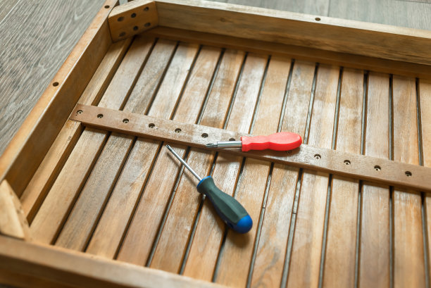 家具组装。一个人收集木制家具。家具装配工用螺丝刀。有工具的师傅修理家具。图片下载