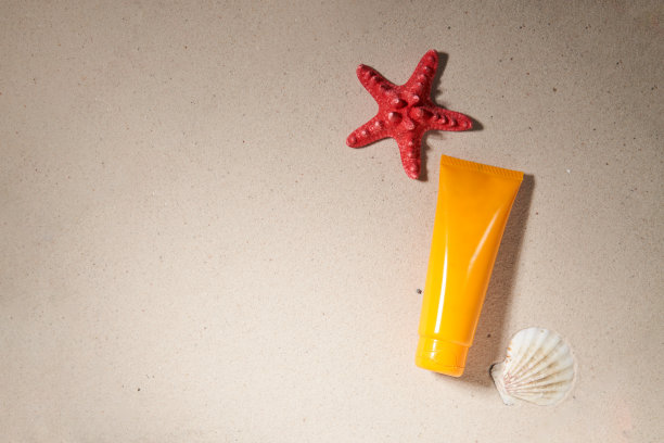 夏季防晒霜在沙滩背景与海星和贝壳。图片下载