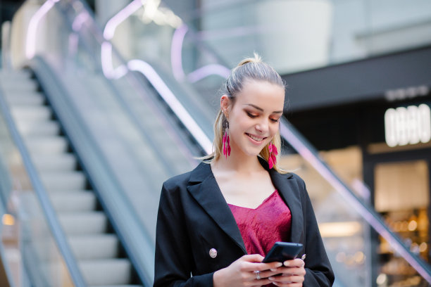 快乐美丽的女人在智能手机上边走边写或读短信图片下载