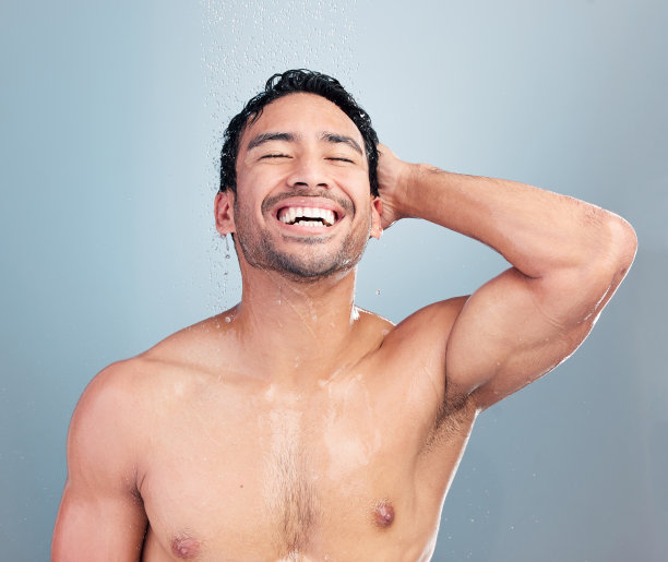 蓝背景下，混血年轻健壮男人在热水淋浴中感到神清气爽。西班牙裔男人在干净的流水下微笑地清洗头发和身体，保持良好卫生习惯图片下载
