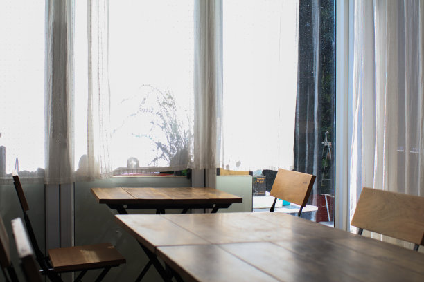 木桌，现代风格的椅子和白色的窗帘。时尚餐厅的室内设计背景餐厅。图片下载