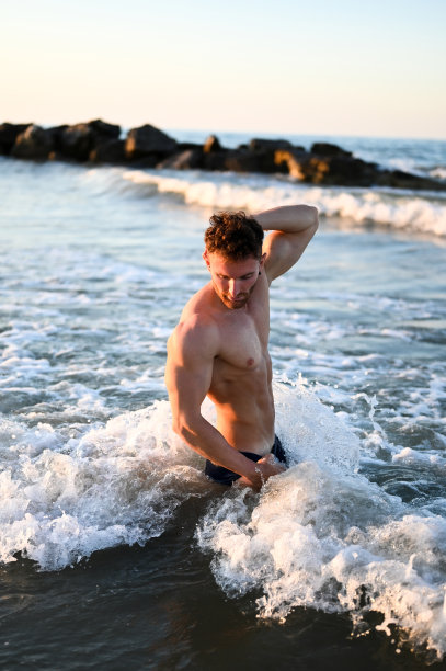 年轻性感男子的肖像在海上与海浪上身。健美运动员英俊的男性。图片下载