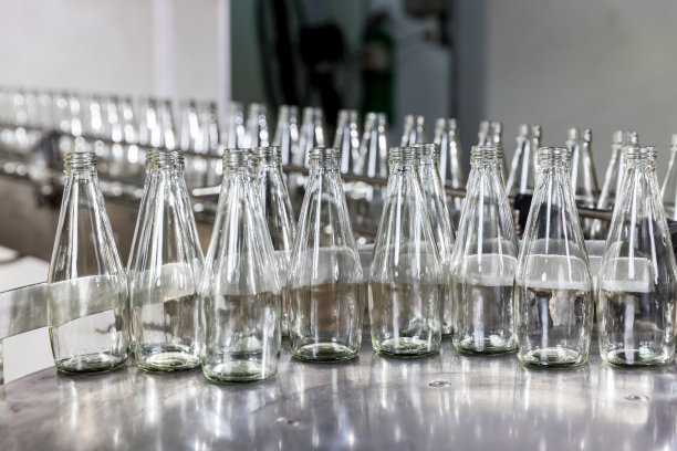 传送带上的空玻璃瓶。装瓶酒精饮料的工厂。在工厂的传送带上装瓶的果汁图片下载