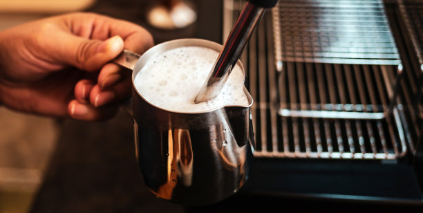 咖啡师用高压蒸汽操作的牛奶起泡器准备卡布奇诺咖啡牛奶的特写图片下载