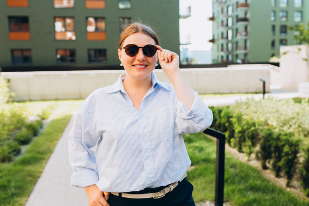 年轻快乐的女人，职业企业家站在办公室的服装，微笑着，看起来很自信，30多岁的女孩穿着蓝色的办公室衬衫，走在街上。成功的事业。图片下载