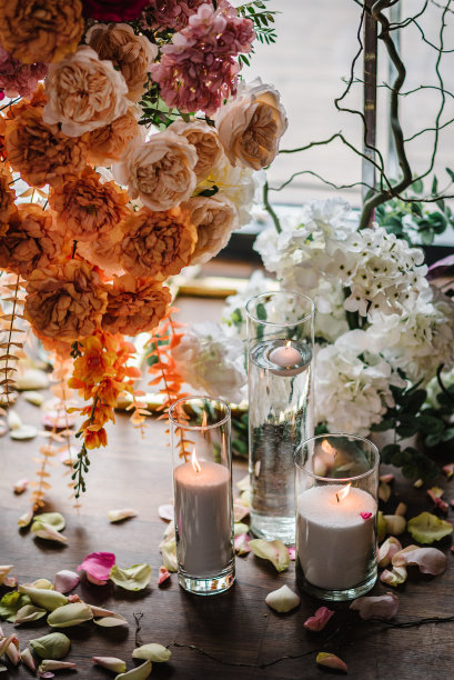 蜡烛，地上的玫瑰花瓣。特写装饰细节。照片墙，粉红色拱门装饰，宴会区，大厅生日派对橙色花朵。豪华婚礼的婚宴。活动装饰图片下载