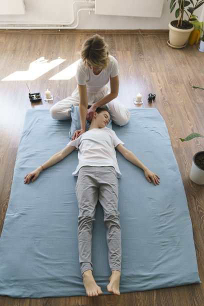 年轻的女按摩师在地板上做泰式按摩，按摩她的脖子和肩膀图片下载