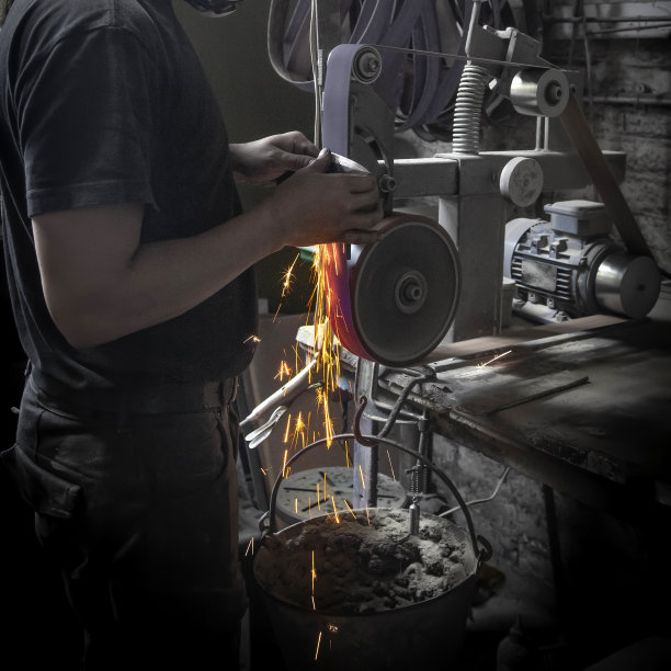一名男子在锻造车间里磨刀，火花四溅图片下载