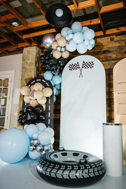 生日装饰用蓝色，棕色，黑色，银色气球为聚会。为庆祝活动做准备。照片墙装饰空间或文字的地方。时髦的装饰有旗帜，赛车，轮子，男孩的车。图片下载