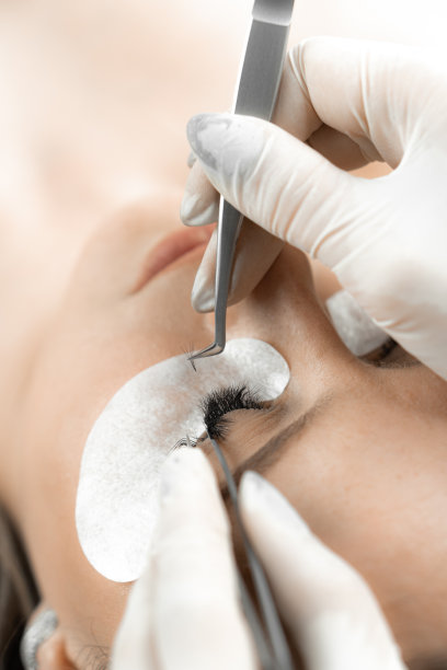 这张照片让你看到了一位美容师的专家之手，他用适当的技术延长睫毛，给脸带来表现力和吸引力。俯视图图片下载