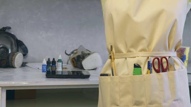 装饰着工具的工作围裙，背景是一张桌子，桌子上放着创意工作室的工作材料图片下载