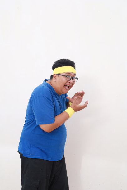 穿着运动服的亚洲超重男子一边站着一边拍手图片下载