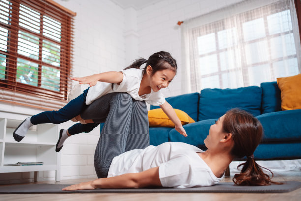 母女俩在家里愉快地一起运动。为柔韧性增强肌肉力量，运动锻炼全家一起训练的理念。图片下载
