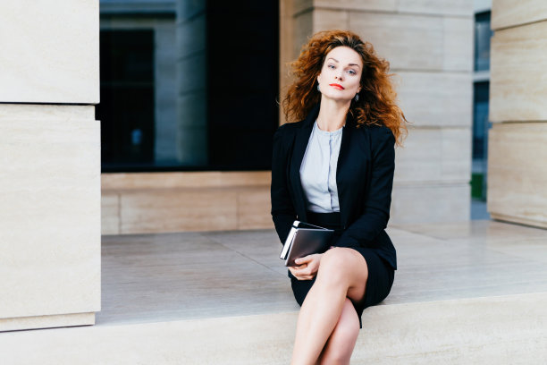 自信的女模特，卷发，红唇，正装，手持平板，跷二郎腿，散发着商务气息。图片下载