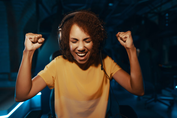 一位年轻女子赢了一场比赛。赢得比赛。霓虹游戏室。图片下载