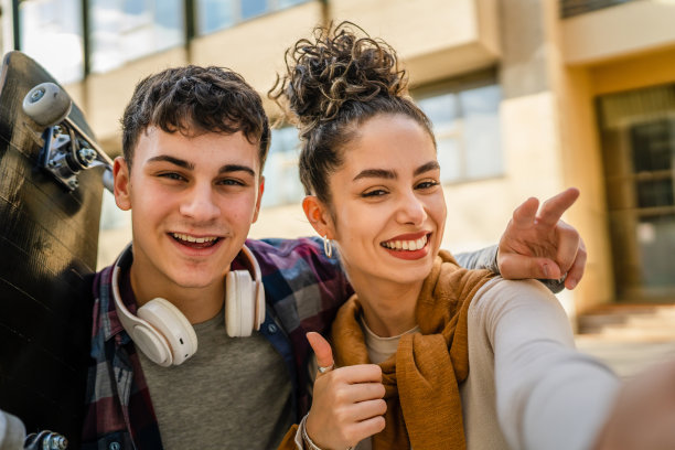 年轻男女在现代建筑旁自拍图片下载