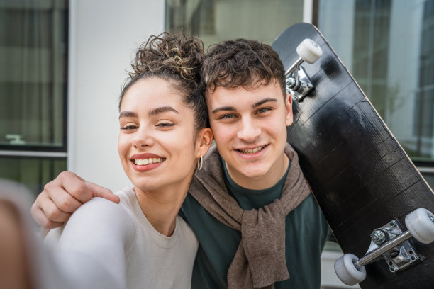 年轻男女在现代建筑旁自拍图片下载