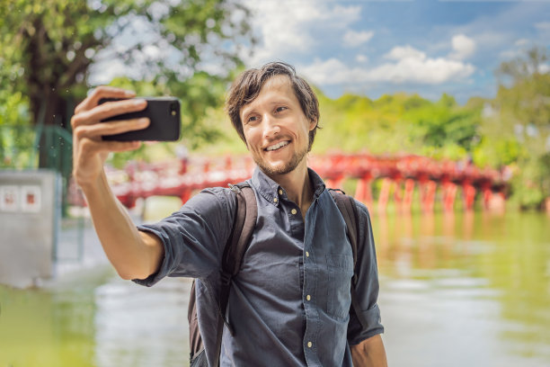 在河内市中心还剑湖中央有树和倒影的公园花园中的红桥为背景的高加索男子旅行者。越南在冠状病毒隔离后重新开放图片下载