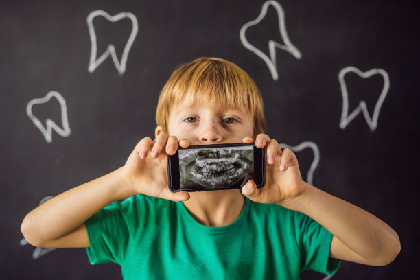 这名男孩展示了他牙齿的x光图像，上面有一颗异常奇怪的多余牙齿。儿童牙科。病人牙齿矫正医师图片下载