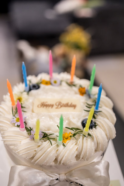 美味的生日椰子蛋糕，在灰色纹理的背景上装饰着美丽的花朵和蜡烛。图片下载