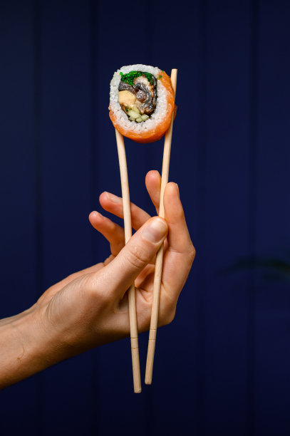 一个费城卷的侧面，手拿竹筷，背景暗图片下载