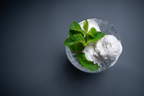 美味的香草冰淇淋与新鲜的薄荷在黑色背景的玻璃碗图片下载