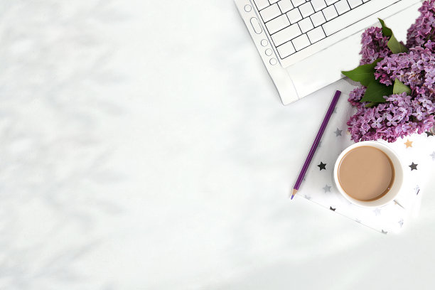 电脑，丁香花和一杯咖啡放在一张浅色的桌子上。现代女性的桌面，家庭办公室。简约的商业理念，居家舒适的生活方式，图片下载