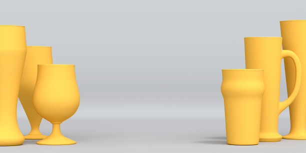 在灰色单色背景上新鲜生啤酒的黄色玻璃杯。图片下载