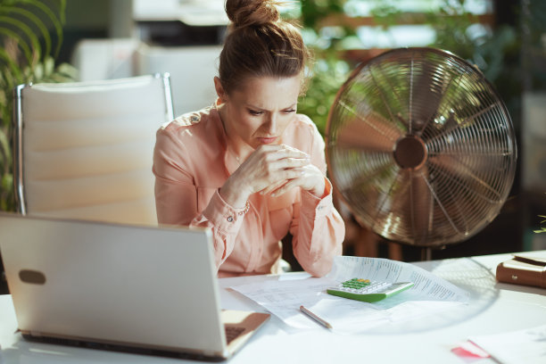 忧心忡忡的现代商务女性正在用电风扇工作图片下载