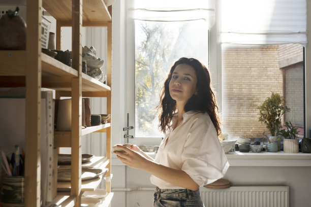 女陶艺家与新收集的陶瓷餐具在工作室的粘土和雕塑。图片下载