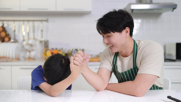 幸福亚洲家庭概念。父子俩在家里玩扳手腕，一起享受时光。小儿子迷路了图片下载